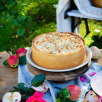 Apfelkuchen auf Gartentisch, mit Blumen dekoriert